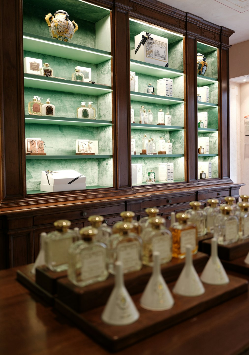 Perfumes y cosméticos de lujo expuestos en estantes forrados de terciopelo.